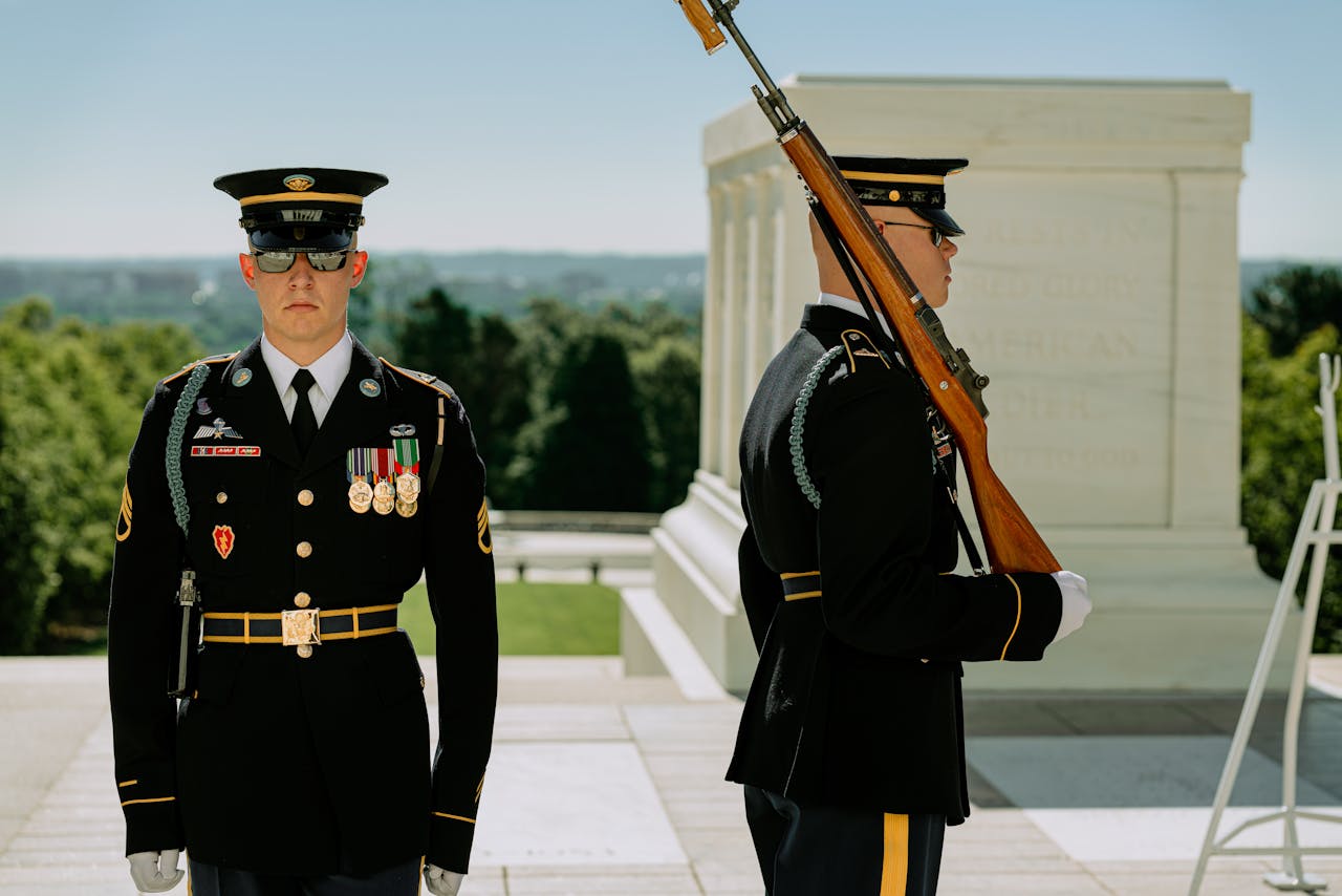 Uniformed military guards perform ceremonial duties outdoors at a national monument.